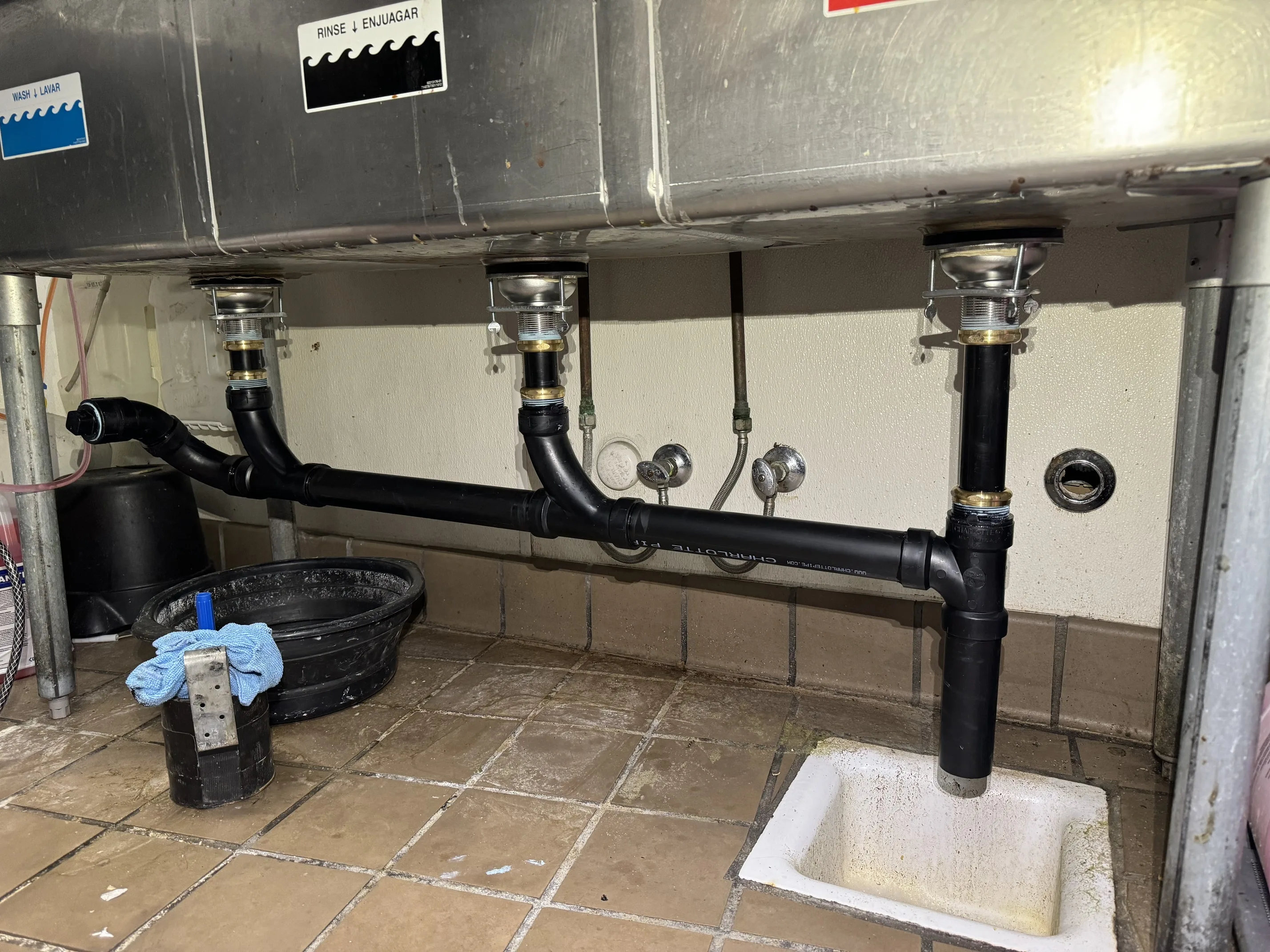 Commercial three-compartment sink plumbing in restaurant kitchen