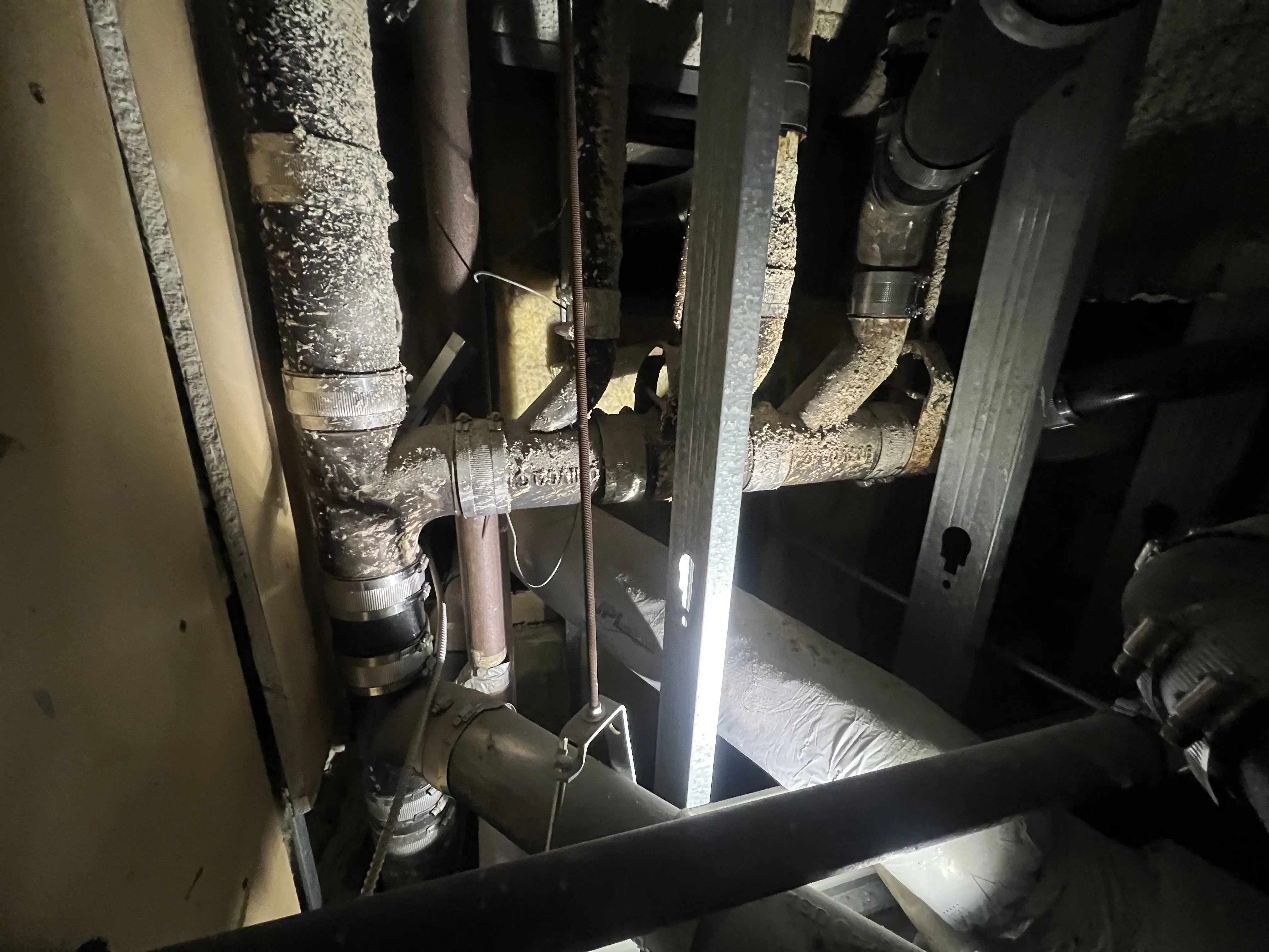 Corroded cast iron drain pipes in overhead pipe chase requiring replacement