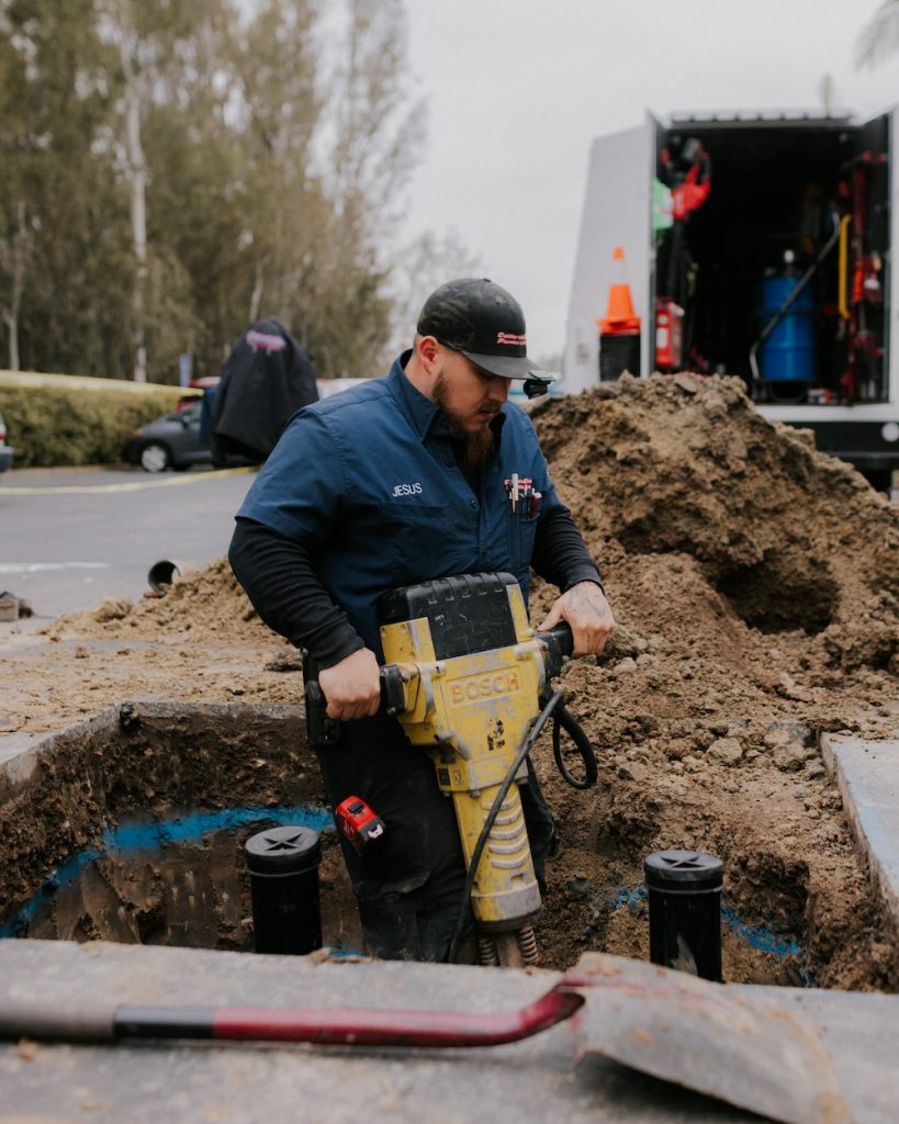 Breaking through concrete to access the sewer line for cleanout installation and repair