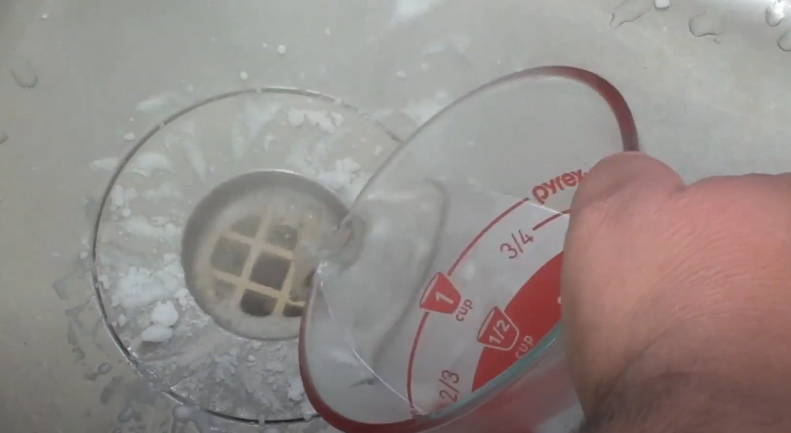 Pouring baking soda and vinegar to clean kitchen sink drain