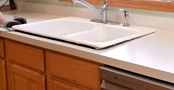 Lifting up old kitchen sink with a pry bar
